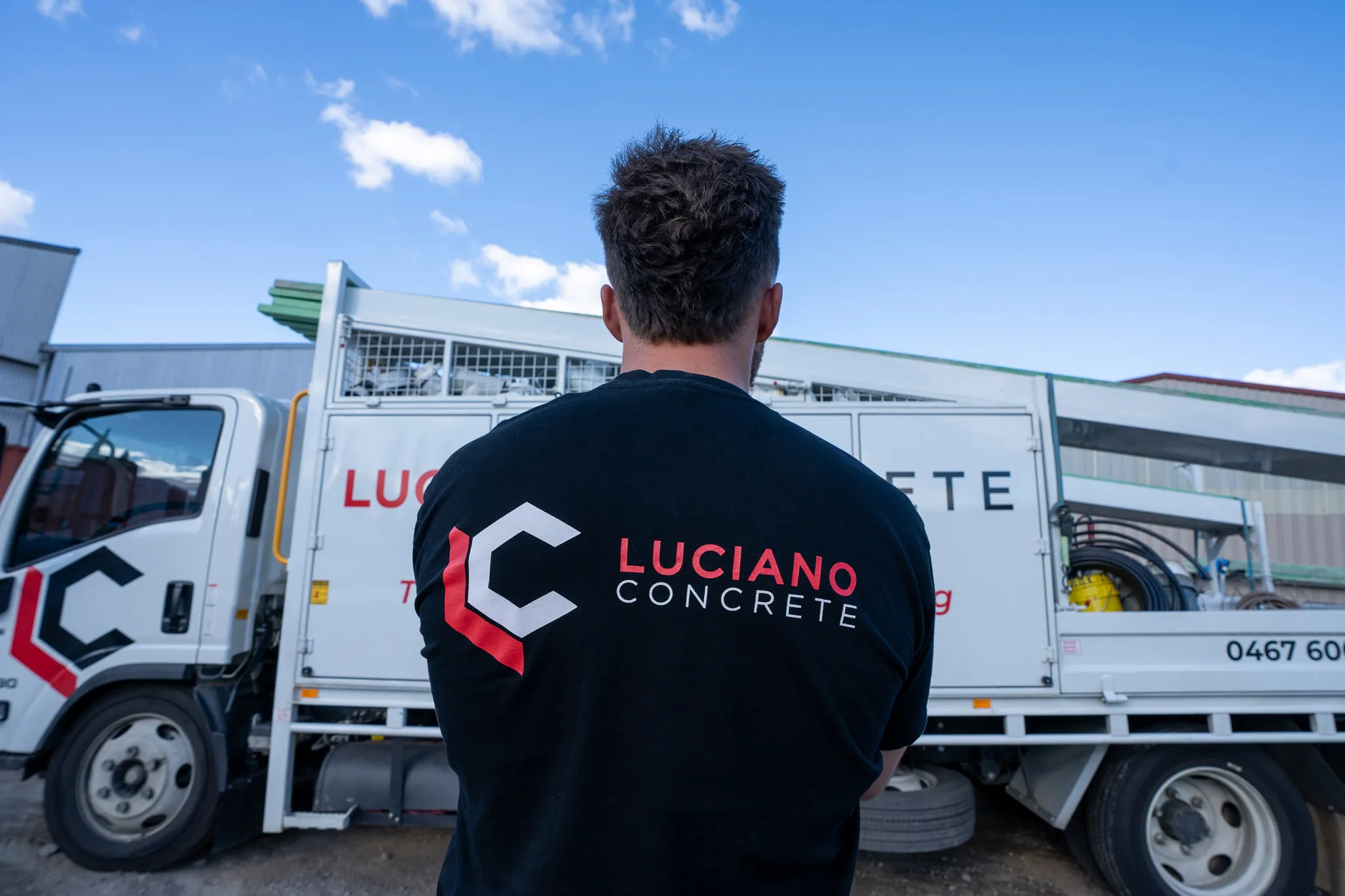 Worker facing a Luciano Concrete truck.