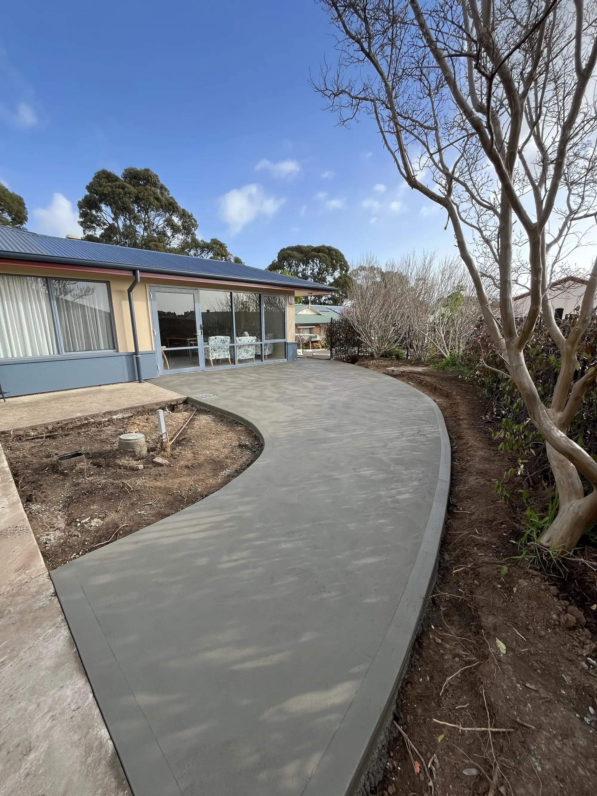 Curved plain concrete pathway on a house backyard.
