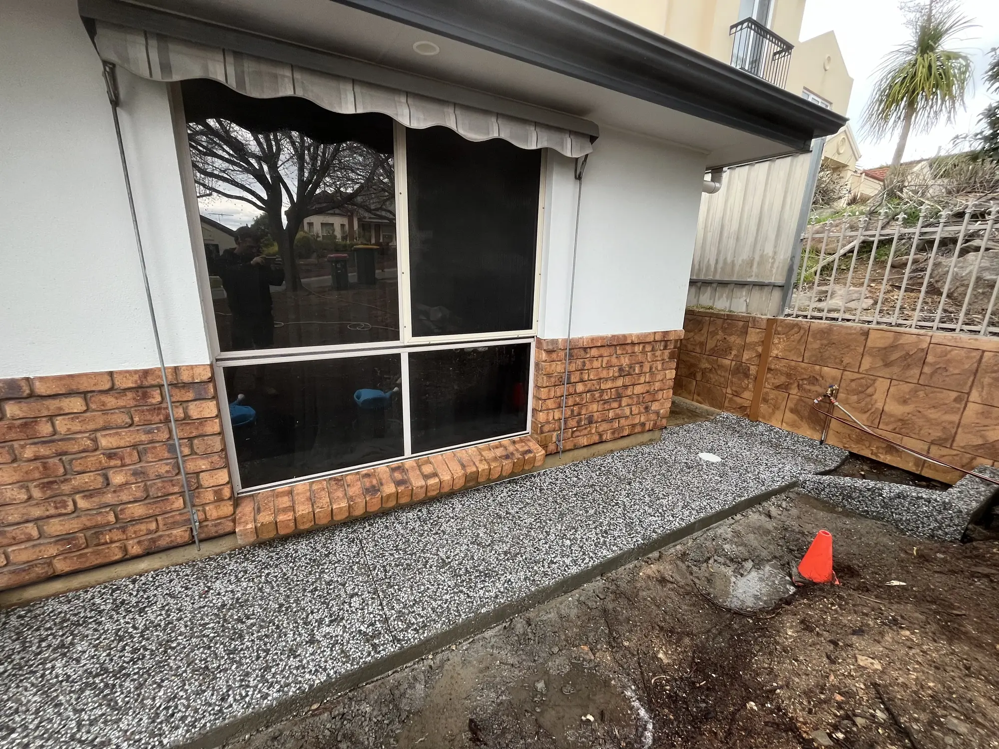 Exposed aggregate concrete near a water tap.