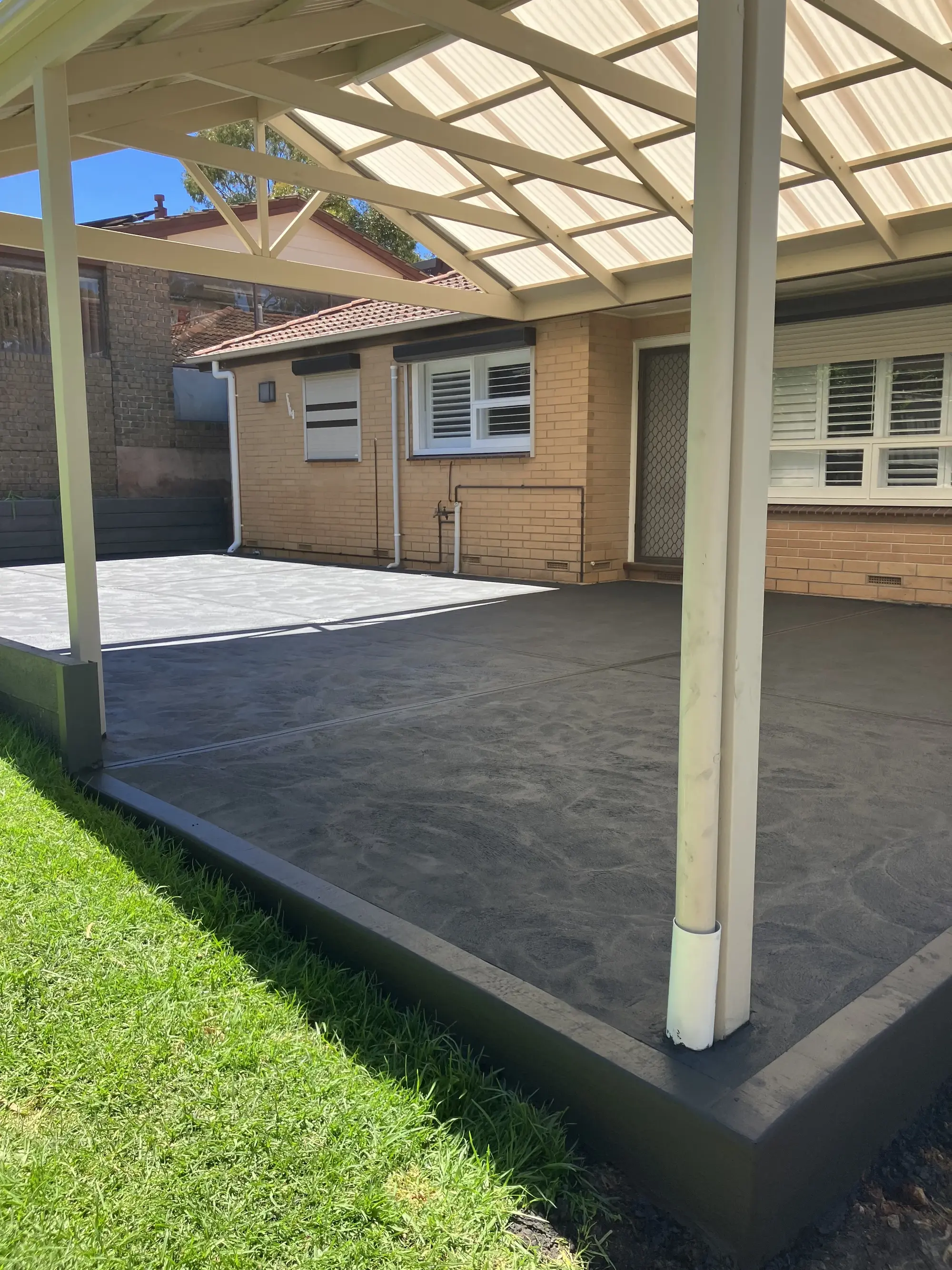 Plain concrete underneath a shed outside a house.